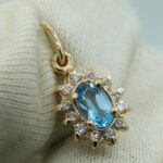 Halo Anhänger aus 585 Roségold mit einem oval facettierten Blau-Topas, umrahmt von funkelnden kleinen Zirkonia
